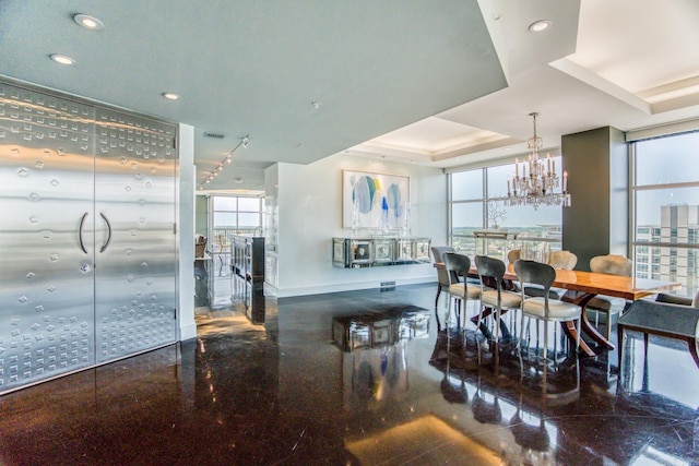 dining area with an inviting chandelier, a raised ceiling, and expansive windows