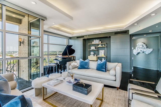 living room with a tray ceiling, a wall of windows, and a healthy amount of sunlight