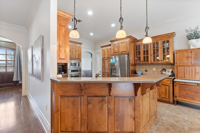 kitchen with backsplash, hanging light fixtures, stainless steel appliances, and ornamental molding