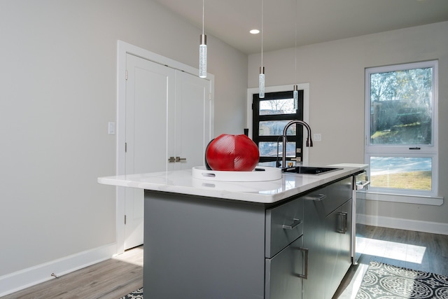 kitchen with plenty of natural light, sink, an island with sink, and decorative light fixtures