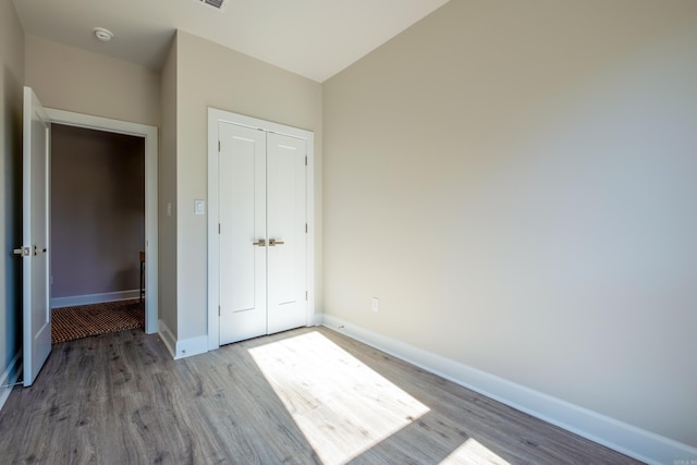 unfurnished bedroom featuring light hardwood / wood-style floors and a closet