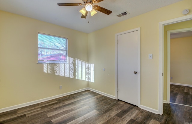 unfurnished bedroom with ceiling fan and dark wood-type flooring