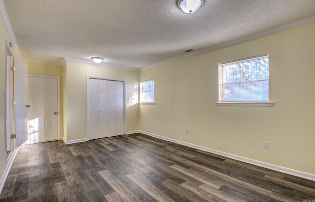 unfurnished bedroom with a textured ceiling, dark hardwood / wood-style floors, crown molding, and a closet