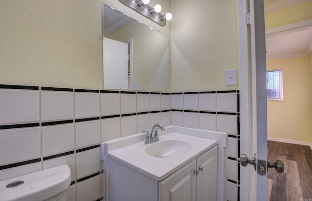 bathroom featuring vanity, toilet, ornamental molding, and tile walls