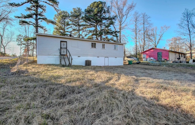 rear view of property featuring a lawn and cooling unit