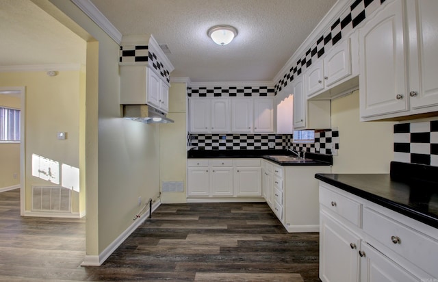 kitchen with a textured ceiling, tasteful backsplash, white cabinetry, and crown molding