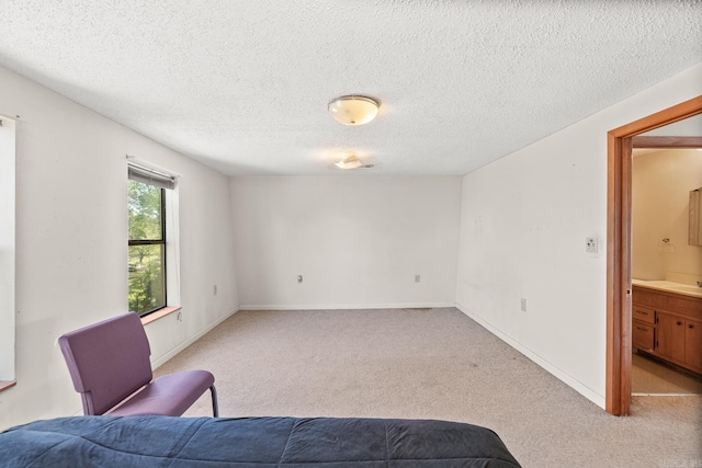 bedroom featuring light carpet, a textured ceiling, and ensuite bath