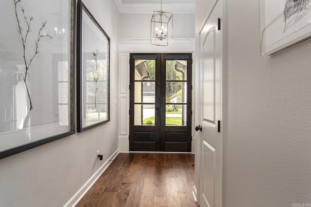 doorway to outside featuring dark hardwood / wood-style floors, crown molding, a chandelier, and french doors