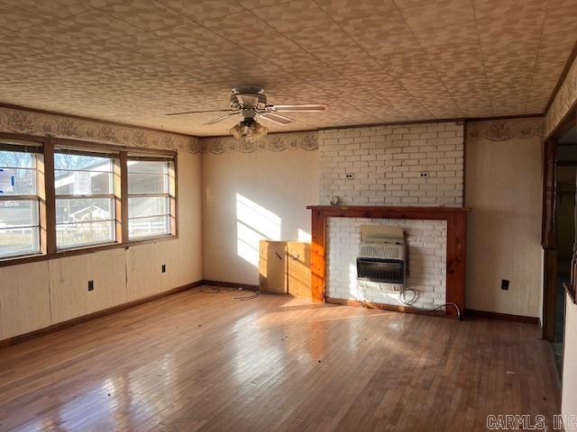 unfurnished living room featuring ceiling fan, hardwood / wood-style floors, a healthy amount of sunlight, and a brick fireplace