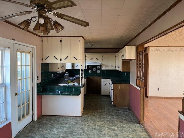 kitchen with white cabinetry, ceiling fan, french doors, black fridge, and decorative backsplash