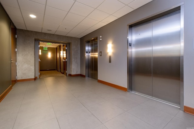 corridor featuring a paneled ceiling and elevator