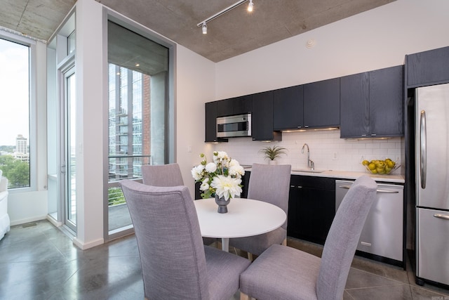 dining space featuring rail lighting, a healthy amount of sunlight, and sink