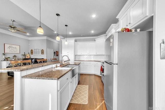 kitchen featuring a breakfast bar, stainless steel appliances, sink, a center island with sink, and white cabinetry