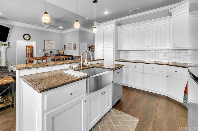 kitchen featuring pendant lighting, dishwasher, white cabinets, sink, and an island with sink