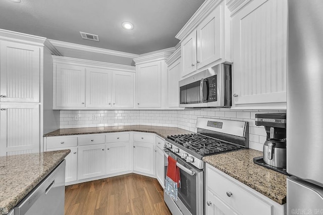 kitchen with white cabinets, decorative backsplash, stainless steel appliances, and crown molding