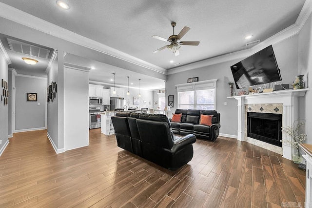 living room featuring a textured ceiling, ceiling fan, crown molding, and a fireplace