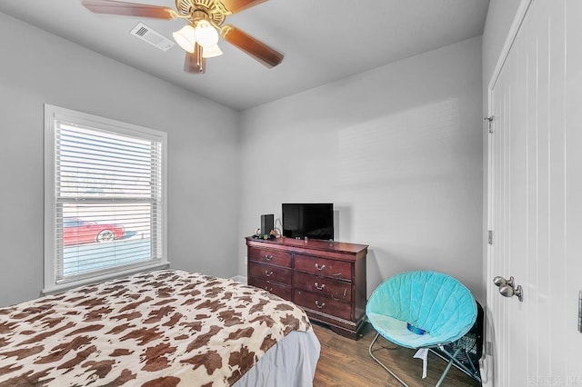 bedroom featuring ceiling fan, dark hardwood / wood-style flooring, and multiple windows