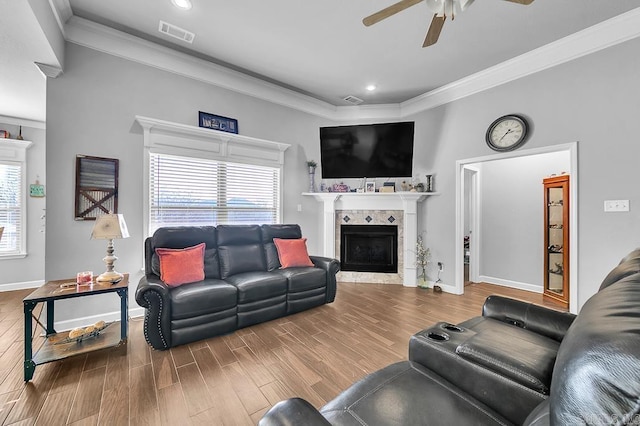 living room with a fireplace, hardwood / wood-style flooring, ceiling fan, and crown molding