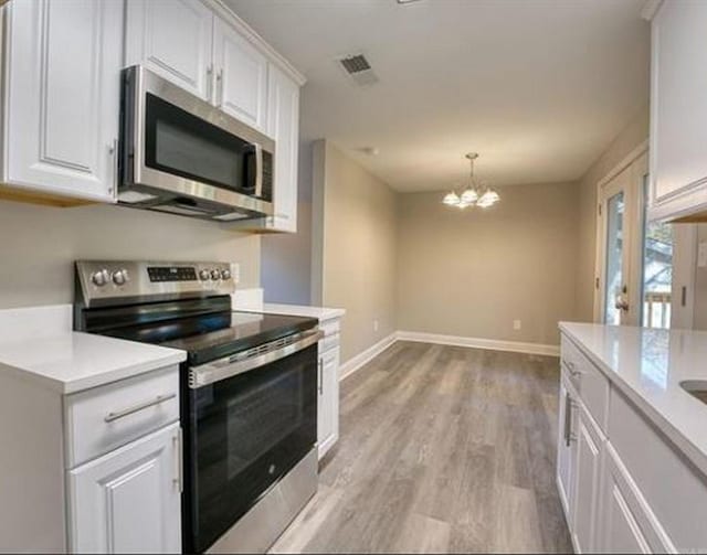 kitchen featuring white cabinets, stainless steel appliances, hanging light fixtures, and a chandelier