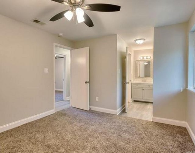 unfurnished bedroom featuring ensuite bathroom, ceiling fan, and light colored carpet