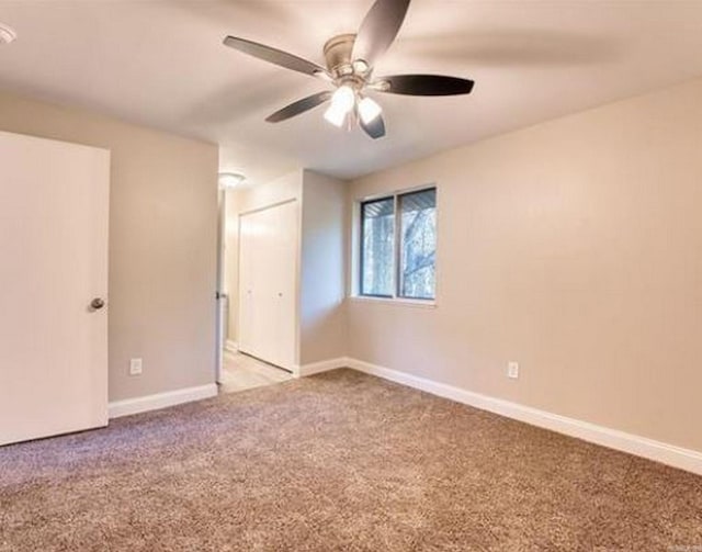 spare room featuring light colored carpet and ceiling fan