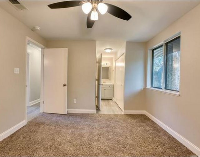 unfurnished bedroom with ensuite bathroom, ceiling fan, and light carpet