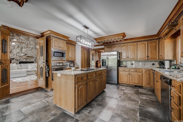 kitchen featuring stainless steel appliances, sink, decorative light fixtures, a fireplace, and a center island