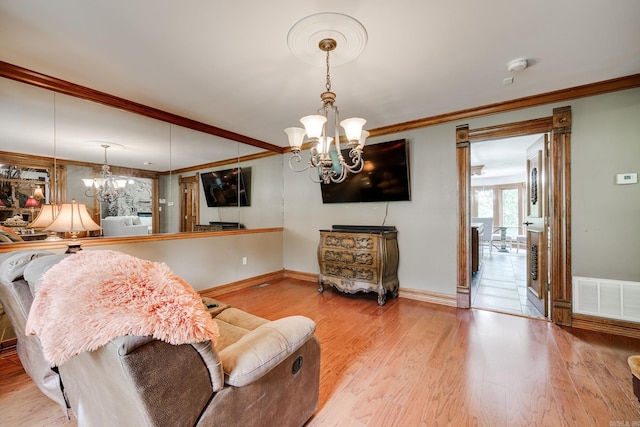 living room with crown molding, a chandelier, and light wood-type flooring