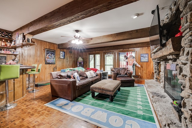 living room with ceiling fan, parquet floors, beamed ceiling, bar, and wooden walls