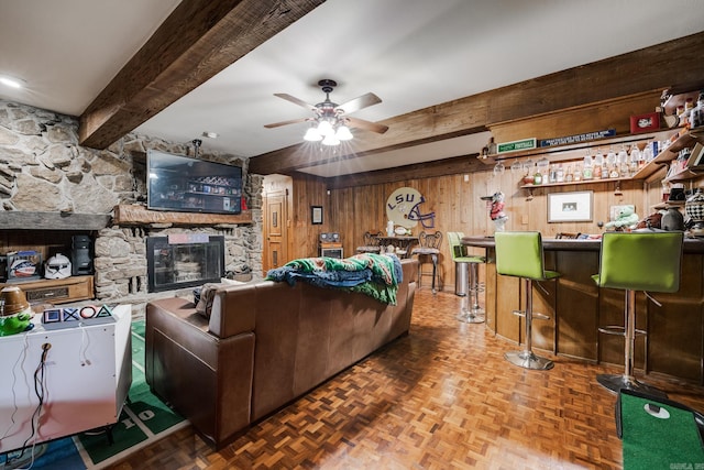 living room featuring parquet flooring, a fireplace, wooden walls, indoor bar, and beamed ceiling