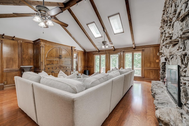 living room with hardwood / wood-style floors, a skylight, high vaulted ceiling, and ceiling fan