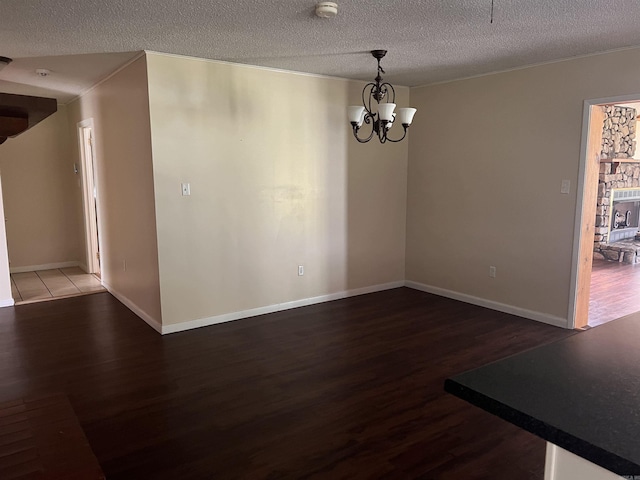 unfurnished dining area with a textured ceiling, dark wood-type flooring, and a notable chandelier