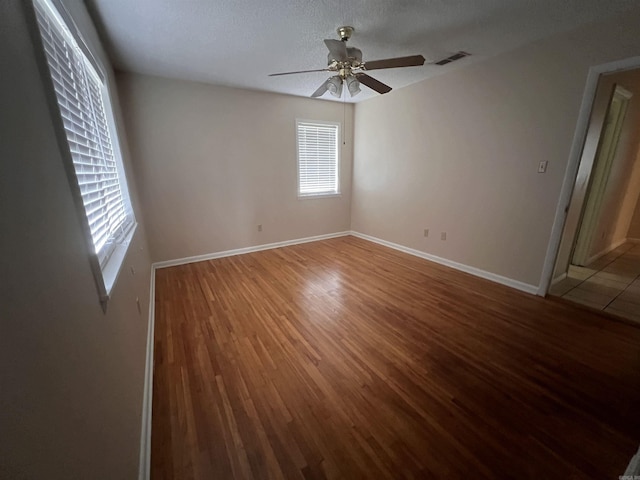 empty room with wood-type flooring, a wealth of natural light, and ceiling fan