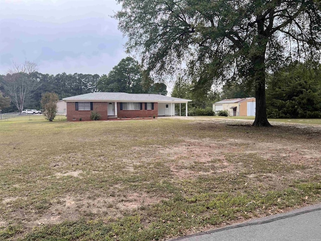 single story home with a carport, a front lawn, and an outdoor structure