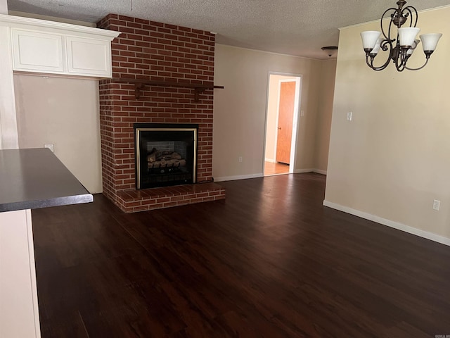 unfurnished living room featuring a textured ceiling, dark hardwood / wood-style floors, a fireplace, and an inviting chandelier