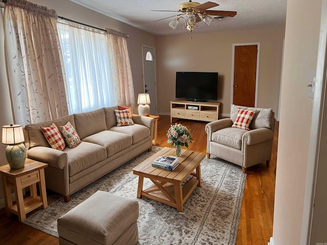 living room with ceiling fan, wood-type flooring, and a textured ceiling