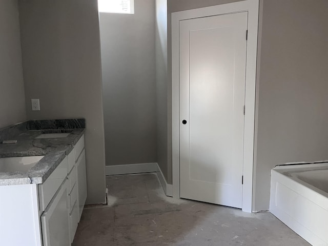 bathroom with a tub, vanity, and concrete flooring