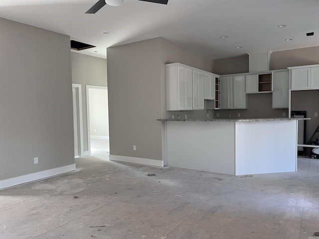 kitchen featuring white cabinets, light stone counters, and ceiling fan