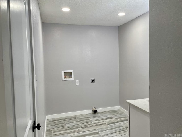 clothes washing area with hookup for an electric dryer, washer hookup, and a textured ceiling