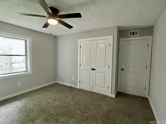 unfurnished bedroom featuring ceiling fan, a closet, a textured ceiling, and dark colored carpet