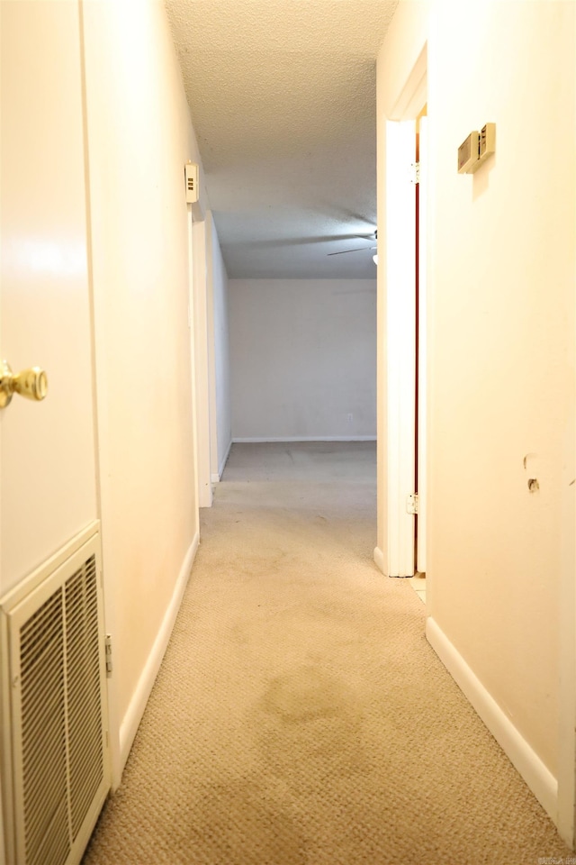 corridor featuring light carpet and a textured ceiling