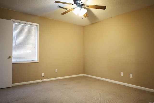 carpeted empty room featuring a textured ceiling, plenty of natural light, and ceiling fan