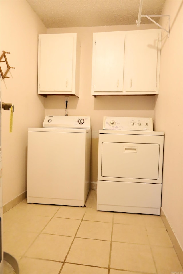 clothes washing area with cabinets, separate washer and dryer, and light tile patterned flooring