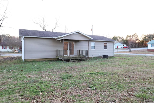 rear view of house with central AC unit and a yard