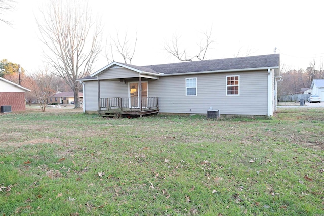 rear view of house with a deck, cooling unit, and a lawn