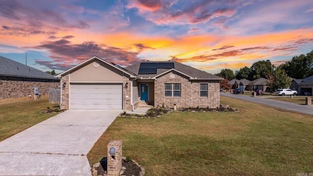 view of front of house with a lawn, a garage, and solar panels