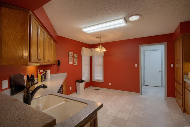 kitchen with a textured ceiling, decorative light fixtures, a notable chandelier, and sink