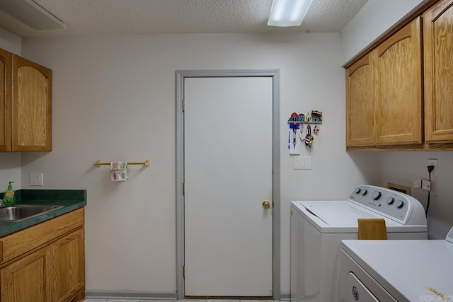 clothes washing area featuring sink, cabinets, independent washer and dryer, and a textured ceiling