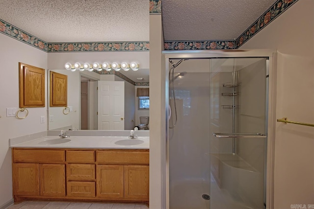 bathroom with tile patterned floors, vanity, a shower with shower door, and a textured ceiling