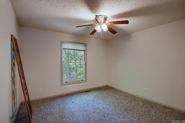 carpeted empty room with ceiling fan and a textured ceiling